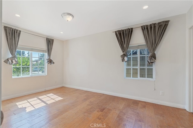 spare room featuring recessed lighting, baseboards, and wood finished floors