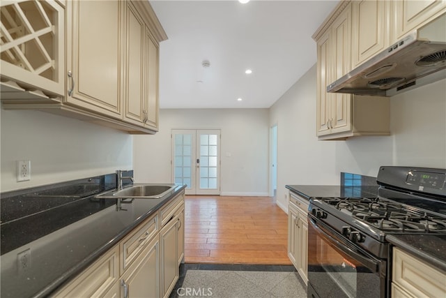 kitchen featuring cream cabinets, black gas range, under cabinet range hood, a sink, and french doors