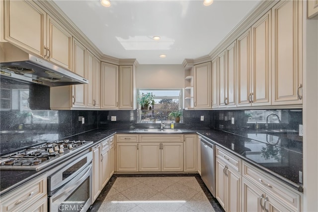 kitchen with stainless steel appliances, cream cabinetry, under cabinet range hood, granite finish floor, and recessed lighting