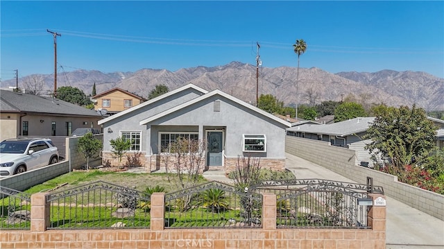 view of front facade featuring stone siding, a fenced front yard, a mountain view, and stucco siding