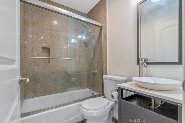 bathroom featuring toilet, shower / bath combination with glass door, and vanity