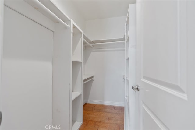 walk in closet with light wood-style flooring