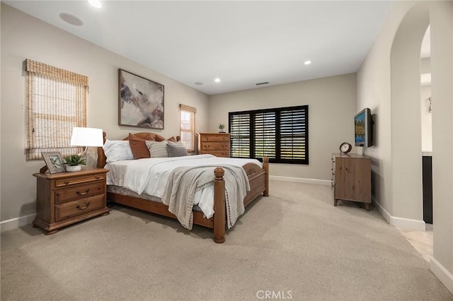 bedroom with arched walkways, recessed lighting, baseboards, and light carpet