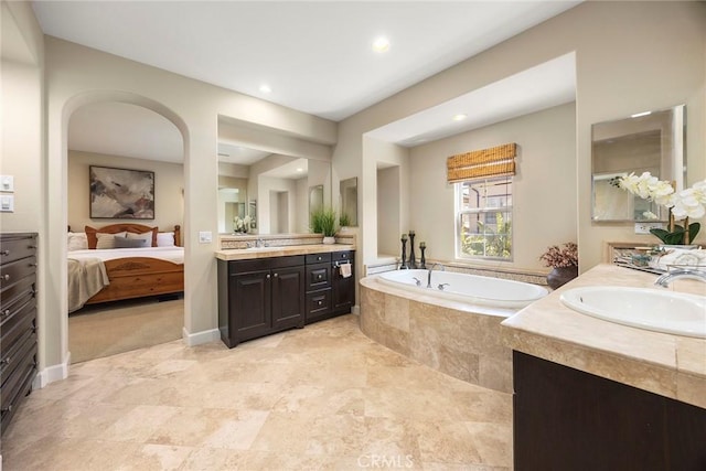 ensuite bathroom featuring a sink, ensuite bath, two vanities, and a bath