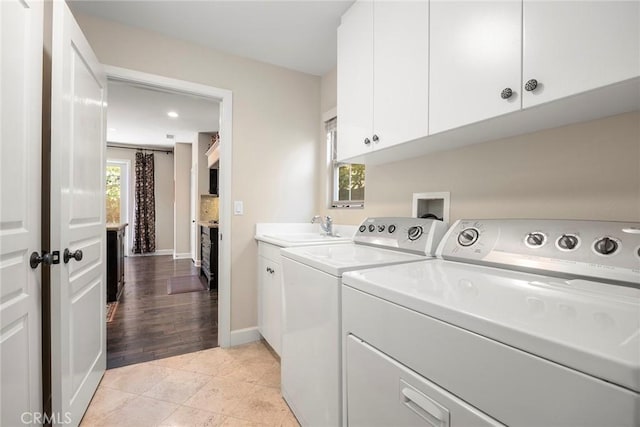 washroom with light tile patterned floors, baseboards, cabinet space, a sink, and washer and dryer