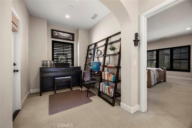 living area featuring arched walkways, visible vents, baseboards, and carpet floors