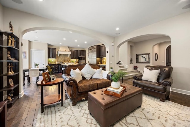 living area with arched walkways, stairs, and light wood finished floors