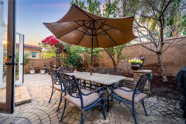 patio terrace at dusk with outdoor dining area and a fenced backyard