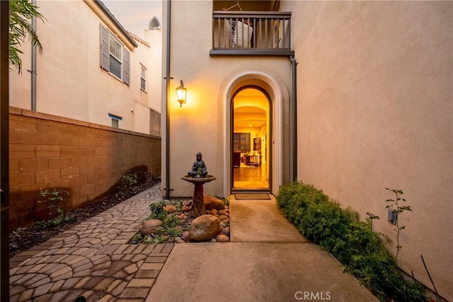 view of exterior entry with stucco siding, a patio, and fence