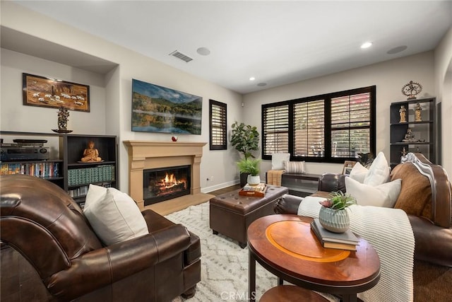 living room featuring visible vents, recessed lighting, baseboards, and a glass covered fireplace