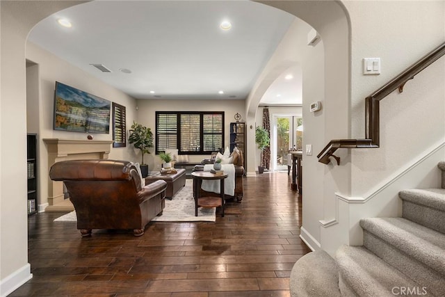 living room featuring visible vents, wood-type flooring, arched walkways, baseboards, and stairs