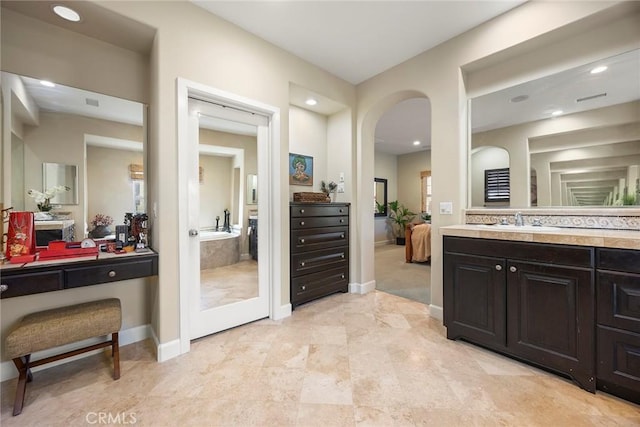 ensuite bathroom featuring connected bathroom, vanity, and baseboards