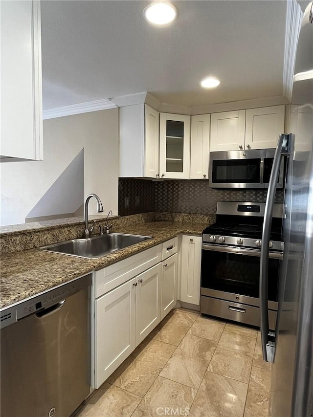 kitchen featuring a sink, white cabinets, ornamental molding, appliances with stainless steel finishes, and backsplash