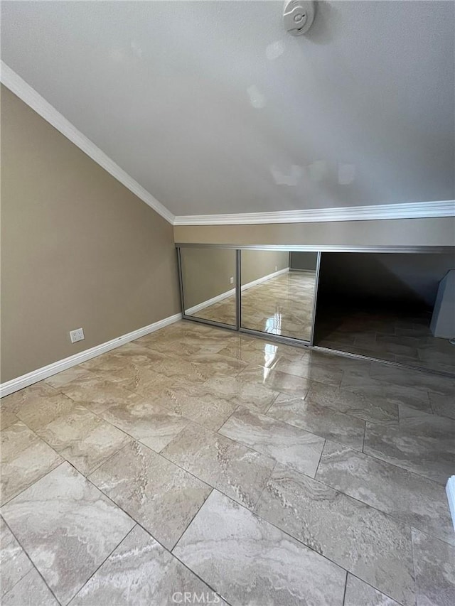 interior space featuring lofted ceiling, baseboards, and crown molding