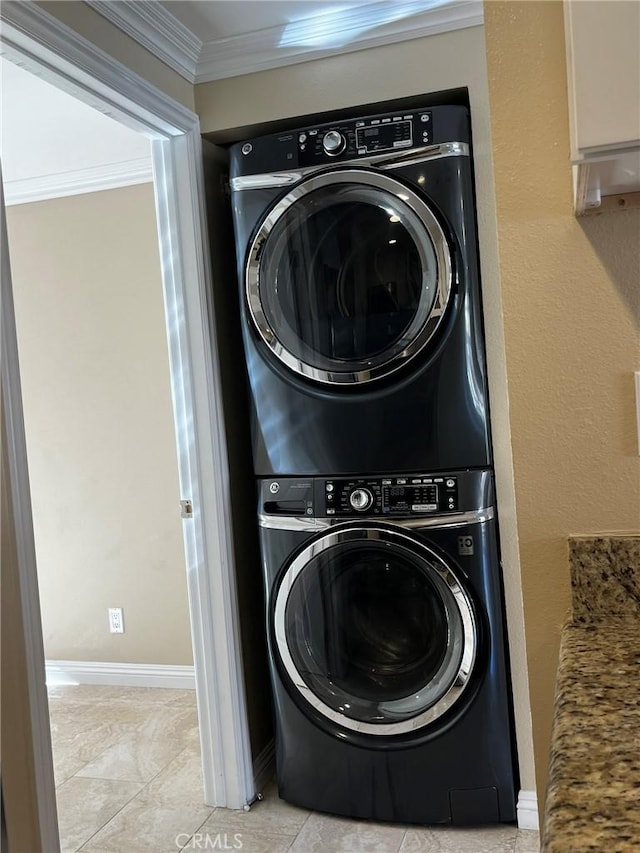 laundry area with laundry area, baseboards, ornamental molding, and stacked washer / drying machine