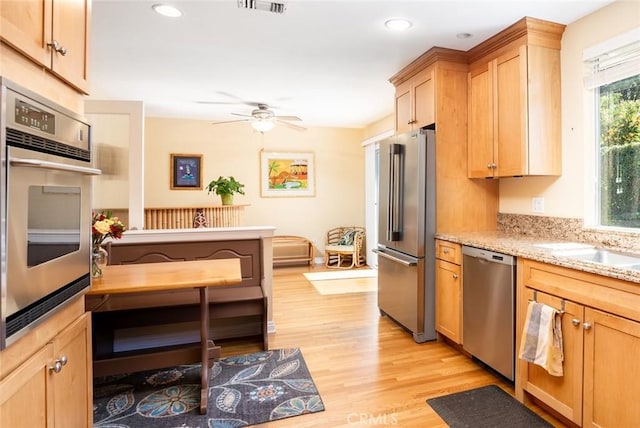 kitchen featuring light wood-style flooring, ceiling fan, appliances with stainless steel finishes, light stone countertops, and recessed lighting