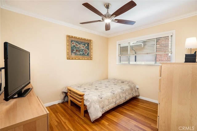 bedroom with ornamental molding, ceiling fan, baseboards, and wood finished floors