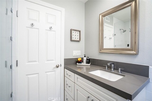 bathroom with visible vents, a stall shower, and vanity