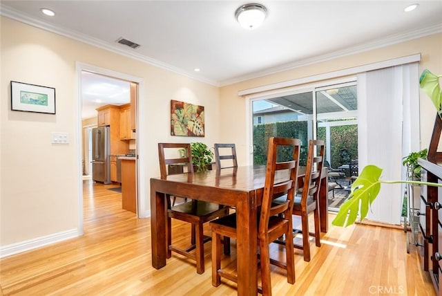 dining room featuring visible vents, crown molding, light wood-style flooring, and baseboards