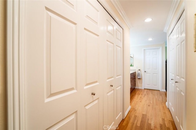 hall with light wood-type flooring, crown molding, baseboards, and recessed lighting