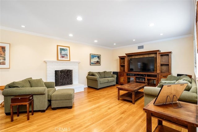 living area featuring crown molding, recessed lighting, a fireplace, and light wood finished floors