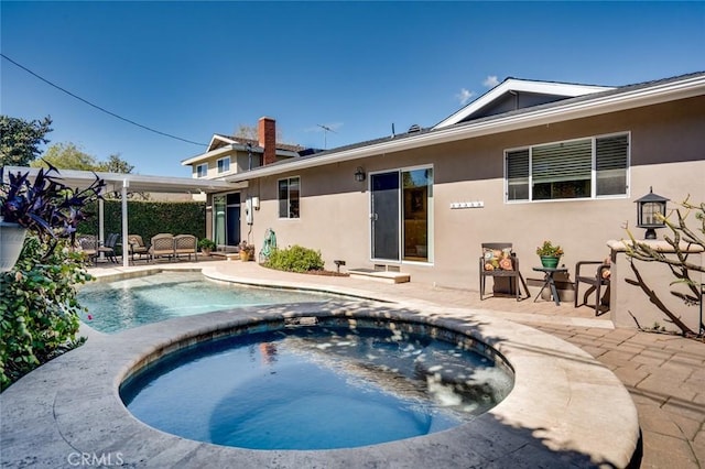 back of property with an in ground hot tub, an outdoor pool, a patio, and stucco siding