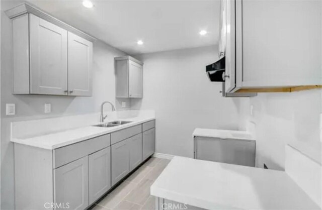 kitchen featuring range hood, recessed lighting, light countertops, a sink, and light wood-type flooring