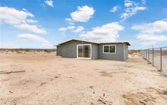 rear view of property with fence and stucco siding