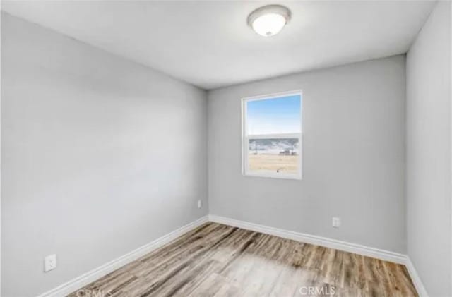 unfurnished room featuring baseboards and wood finished floors