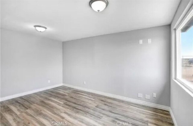 unfurnished room with baseboards and wood finished floors