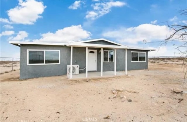 view of front of house featuring ac unit, a patio area, fence, and stucco siding