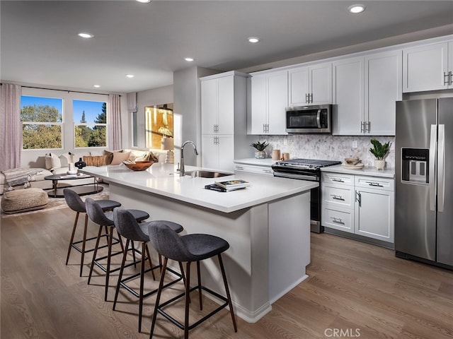 kitchen featuring appliances with stainless steel finishes, a sink, a kitchen breakfast bar, and dark wood-style floors