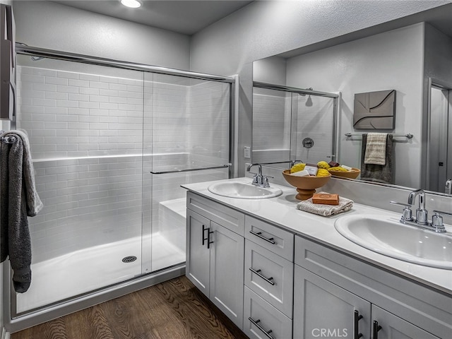 bathroom with a sink, a shower stall, and wood finished floors