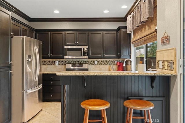 kitchen with light tile patterned floors, stainless steel appliances, tasteful backsplash, and ornamental molding