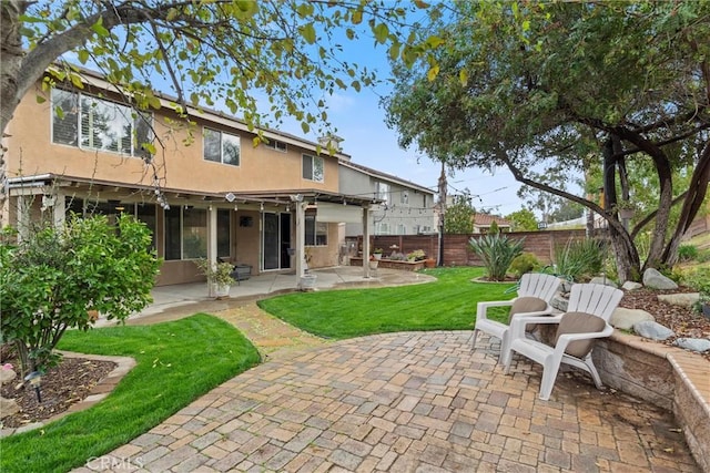 back of house featuring a patio area, a yard, fence, and stucco siding