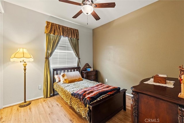 bedroom featuring ceiling fan, baseboards, and wood finished floors