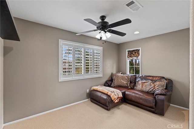 living area featuring a healthy amount of sunlight, baseboards, visible vents, and carpet flooring