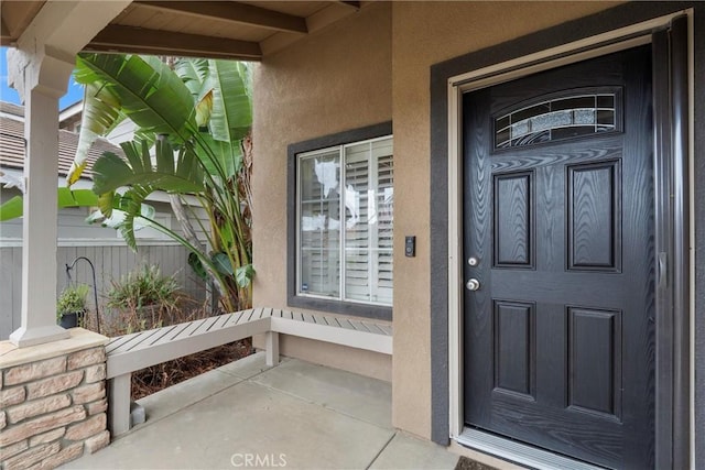 property entrance featuring a porch and stucco siding