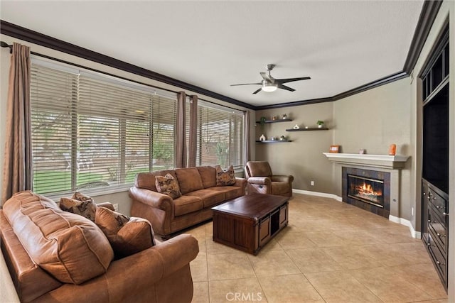 living area featuring light tile patterned floors, baseboards, a tile fireplace, ceiling fan, and ornamental molding