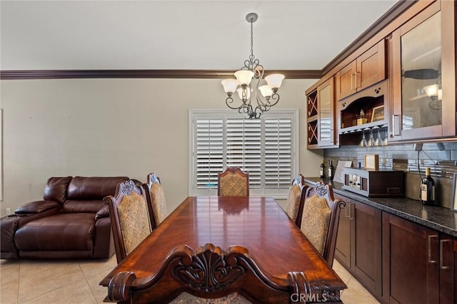 dining room with light tile patterned floors, ornamental molding, and an inviting chandelier