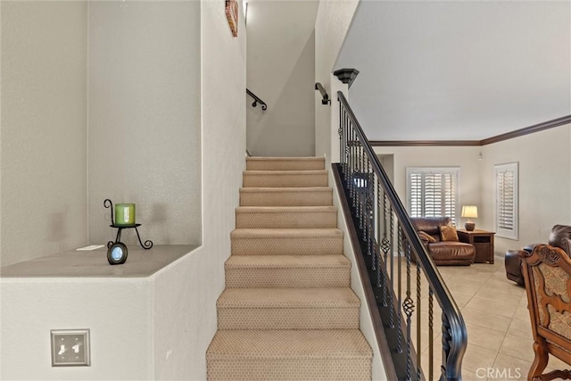 stairs featuring tile patterned floors and crown molding