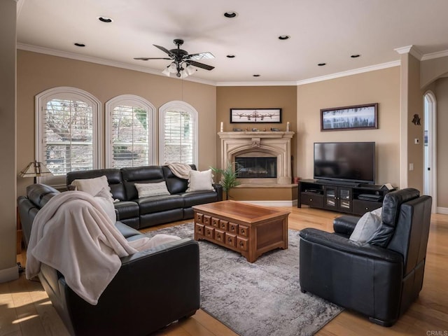 living area featuring a glass covered fireplace, crown molding, and wood finished floors