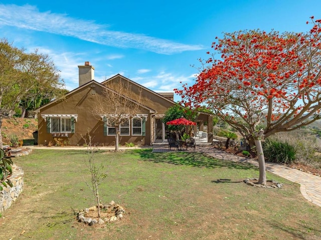 rear view of property featuring a chimney and a lawn