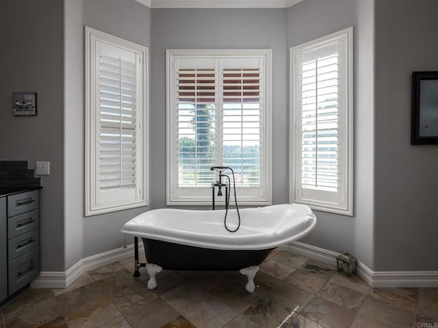 bathroom featuring stone finish floor, a freestanding tub, and baseboards