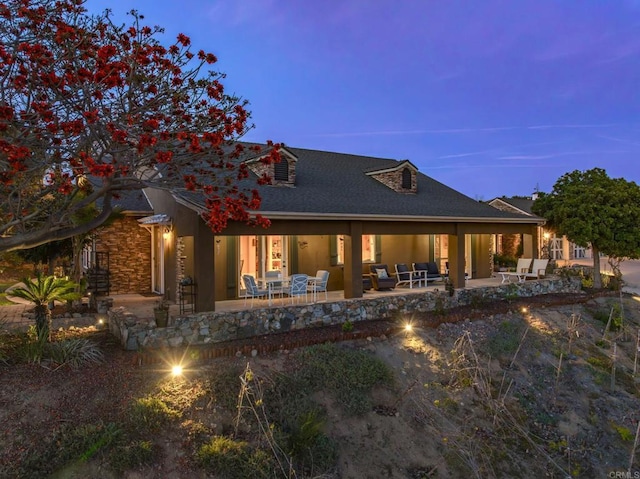 back of house at dusk featuring a swimming pool and a patio