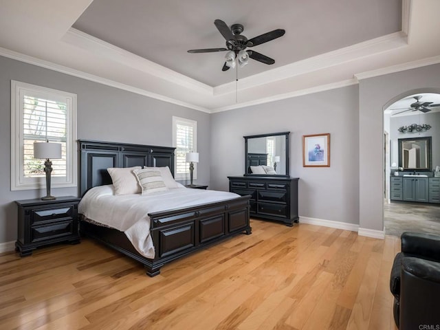 bedroom featuring light wood-type flooring, a raised ceiling, and baseboards