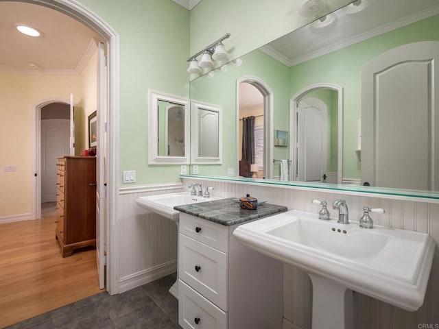 full bath with ornamental molding, a sink, and wood finished floors