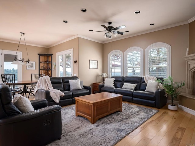 living area featuring light wood-style floors, baseboards, ornamental molding, and ceiling fan