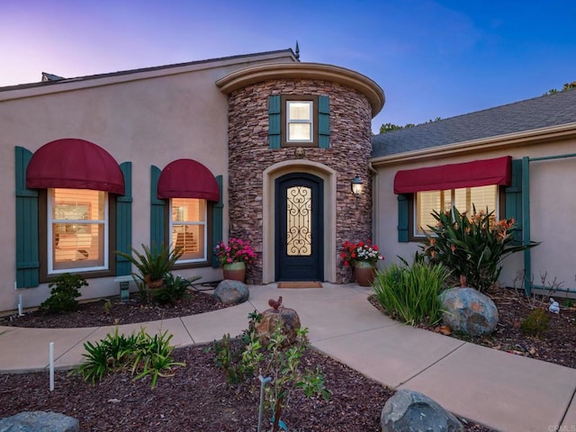 view of front of home featuring stone siding and stucco siding