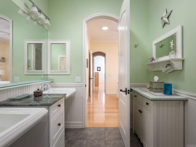 bathroom with a wainscoted wall, tile patterned flooring, and vanity